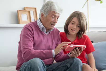 Photo of a grandfather and a grandson looking at phone together