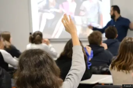 Children in a classroom raising hands