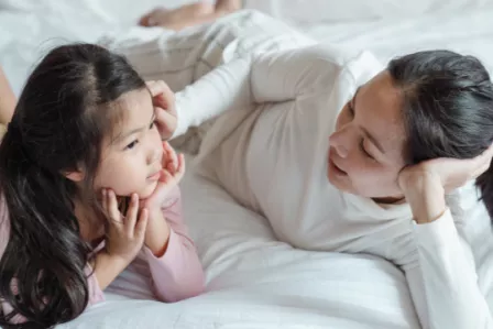 A mother speaking to her daughter on a bed