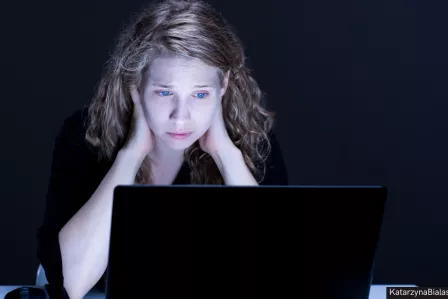 A young teenager girl looking worried in front of a laptop