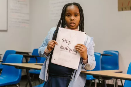 Girl holding a textbook with the words Stop Bullying on it