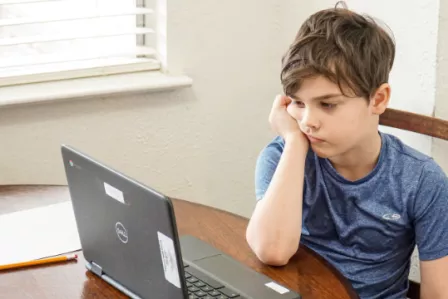 Boy sitting behind a computer looking sad