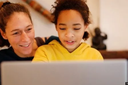 A mother and daughter looking at a laptop screen together