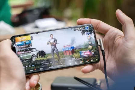 Hands holding a smartphone with the image of a video game character