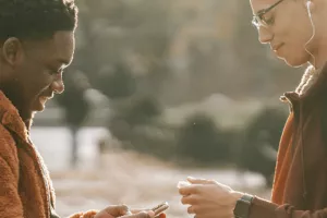 Two teenage guys with mobile phones standing towards each other looking content.