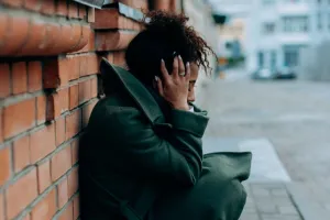 Preoccupied female teenager lying against a wall