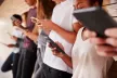 A group of five young people all holding their own smartphone and looking at it.