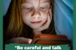 Young child looking at mobile phone screen under a quilt.