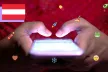 View of two hands tapping on a smartphone screen, and lots of social media icons surrounding the phone.