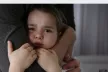 Little girl in tears, being held by the arm of a person 