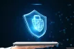 Hands holding a laptop with a virtual shield on top