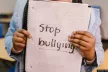 A pair of hands hold a paper sheet upon which is written "no bullying"