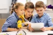 Two boys and a girl looking at the screen of a tablet