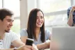 Smiling young people seated at a desk with a laptop