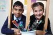 Two smiling children holding paintbrushes