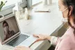 Girl wearing a facemask,seated at a desk using a laptop for online learning