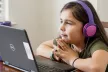 Young girl with headphones looking at a laptop
