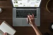 Birds eye view of a laptop on a desk, with a hand typing