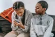 Children looking at smartphone and sitting on a sofa