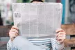 Person sitting on a bench while reading the newspaper