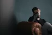 Man sat on a sofa, looking distraught with his head in his hand