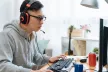 Teenage boy using a desktop computer wearing headphones and a mic