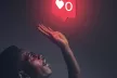 A young man trying to reach for a "likes" icon