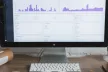 A report showing on a desktop computer screen, and an open notepad on a desk
