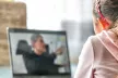 Girl following school lesson on her laptop with male teacher is speaking