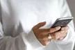 Girl holding Phone wearing white jumper