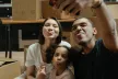 Two parents and a toddler making funny faces as they take a selfie together