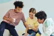 A group of three children looking at a smartphone and smiling