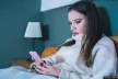 A teenager girl in bed looking at her phone