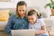 A mother and her son sitting on the floor and looking at a laptop