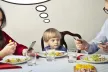 Two parents and a child eating dinner; both parents are engrossed in their mobile phones