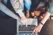 A group of young people pointing at a laptop screen