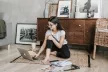 Woman sitting on a lounge floor with a laptop and a pile of magazines