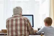 Rear view of a grandfather and grandson using a desktop computer together