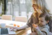 Mother using a laptop with a young child on her lap