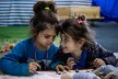 Two young Romani girls play and color at a designated "safe space" for refugee children 