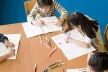Children colouring a book on a table