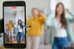 Two adolescents dancing in front of a smartphone on a tripod, recording themselves.