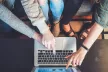 Group of teenagers gathered around a laptop