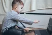 Young child pointing at open laptop in front of him