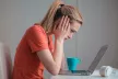 Girl with her head in her hands looking at a laptop screen