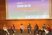 Birdview of the conference venue with the stage and a panel of eight young people