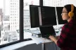 A woman working in front of several computer screens