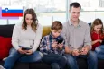 A mom and dad with their two kids all on their phone 