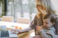 Mother using a laptop with a young child on her lap
