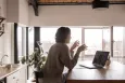 Woman using a laptop sat at a kitchen counter